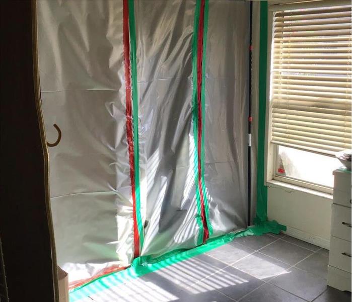 A doorway is sealed with plastic sheeting and taped closed for restoration purposes