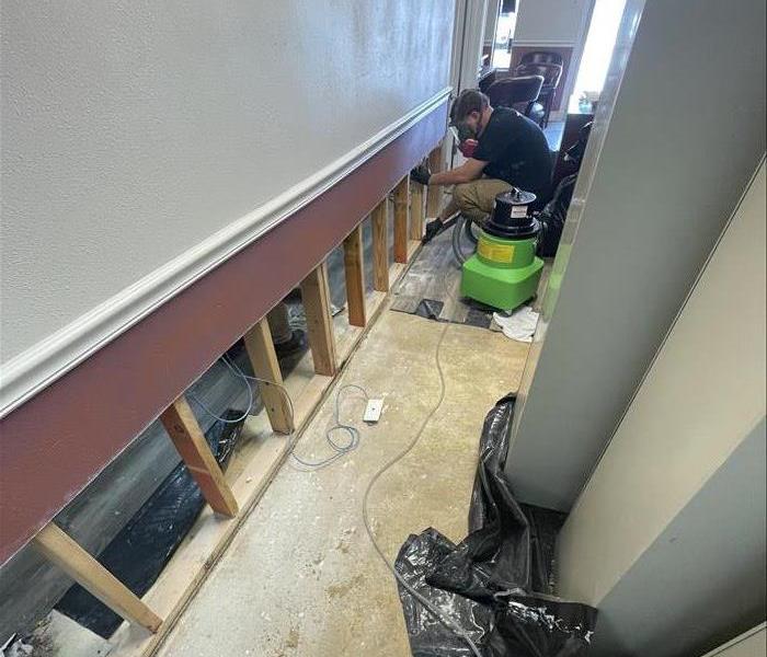 SERVPRO crew member in the middle of repairing a wall that has sustained water damage